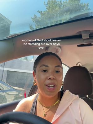 A woman with dark hair and gold hoop earrings is filmed from the chest up, seated in a car. The shot is framed with the car's interior visible: the ceiling, windshield, and headrest. The sunlight washes over the scene, creating a bright and warm ambiance. Out the window, a glimpse of a house and trees is visible. The text overlay across the top reads, 'women of God should never be stressing out over boys ever'.