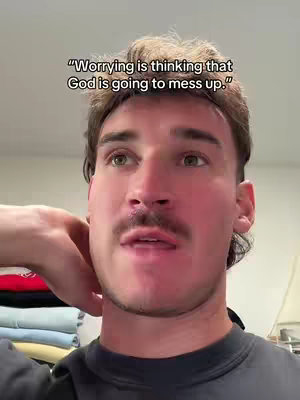 A man with short brown hair and a mustache is looking slightly upwards and to the left, with a quote overlayed on top of the image. The background appears to be an off-white wall, and the man is wearing a black t-shirt.