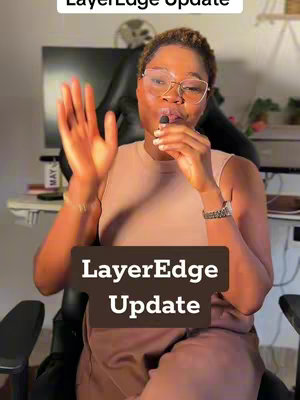 A woman with glasses and a microphone is in a well-lit room. She is gesturing with her hand, with text overlaying the image. A computer monitor is visible in the background.