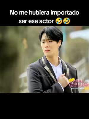 The image is a vertical frame taken from a video, featuring a young Asian man as the central subject. He gazes towards the left with a concerned and slightly surprised expression. The man, with dark hair styled neatly, is dressed in a dark blazer over a white dress shirt, suggesting a formal or professional setting. The background appears blurred, possibly an outdoor setting, with hints of greenery and a building, allowing the focus to stay on the figure. There's text overlaid at the top.