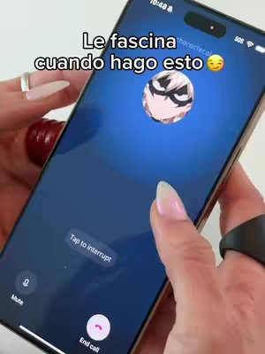 A phone displaying an incoming video call from an anime character. The phone is held in front of a white background with the person's hands visible with long nails.