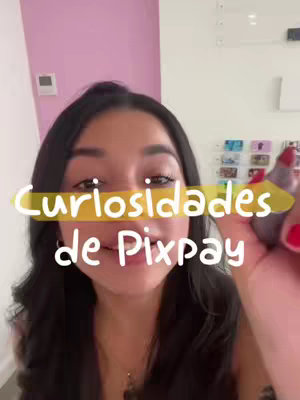 A woman with long black hair is centered in a vertical video frame. She holds a purple pen in her right hand against her cheek, while another hand, with red nail polish, is beside it, seemingly holding the phone. Across her face, from cheek to cheek, runs a horizontal yellow banner with the text. Behind her is a blank wall and a pink wall.