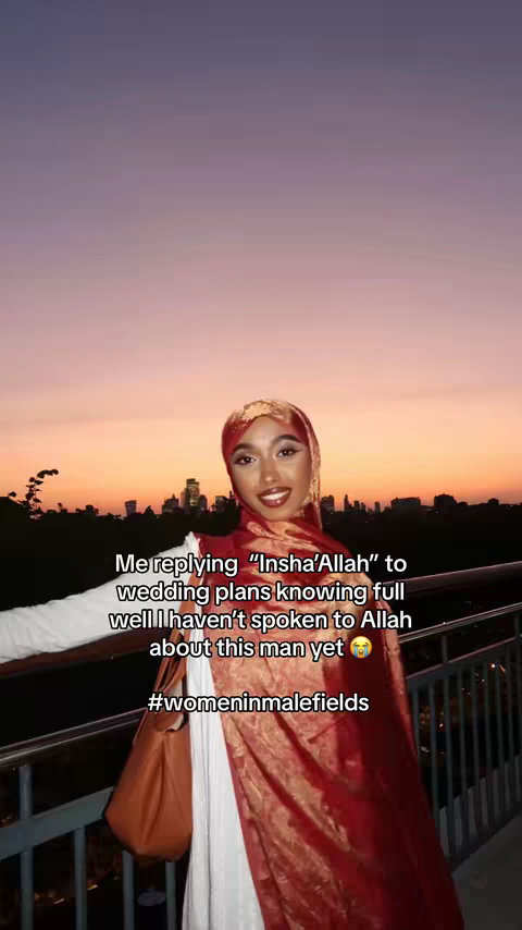 A woman wearing a hijab and a patterned red wrap stands outdoors at dusk. The background features a cityscape with an orange and purple sky. Text overlays her image.