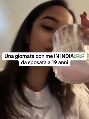 A woman holding a glass of water, with text overlayed on the image reading "Una giornata con me IN INDIA da sposata a 19 anni."