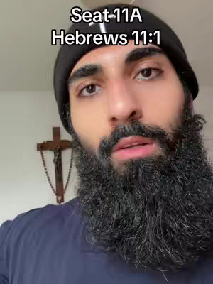 A close-up shot of a bearded man wearing a black beanie, with visible text overlays. Behind him, a cross hangs on the wall.