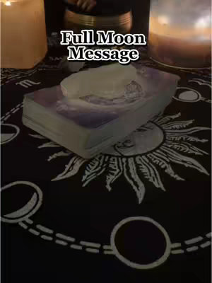 A low-angle shot focusing on a tarot setup with a deck of cards, a crystal, and candles creating a mystic ambiance. The scene is set on a black cloth with a celestial sun pattern.