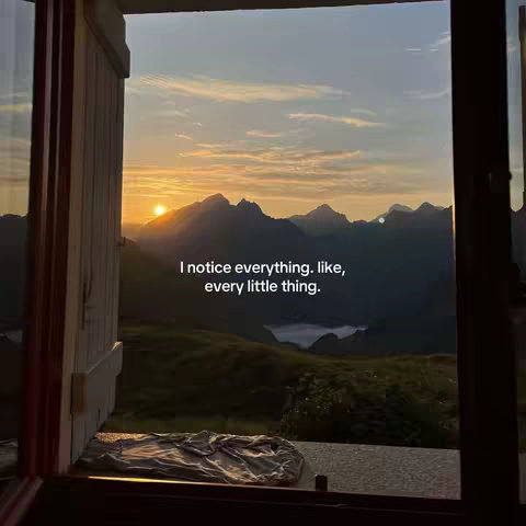 A serene landscape view through a window frame, revealing a sunset over mountain peaks. The warm glow of the sun is prominent, with text overlayed in the center.