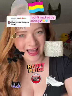 A selfie-style shot featuring a fair-skinned person with long red hair and an open mouth. Overlayed are multiple stickers like earrings, a purse, bows and a pansexual flag. The person is wearing a black t-shirt with a button and has a red mouth. There is a white high-heeled shoe sticker added. The background is blurry with domestic setting elements.