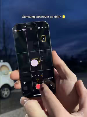 The cover image presents a smartphone, likely an iPhone, held by hands. The screen displays a camera interface with the moon as the subject. In the background, a dark sky is visible. Overlaid text reads, 'Samsung can never do this?'. The composition is focused on the phone and its photographic capabilities.