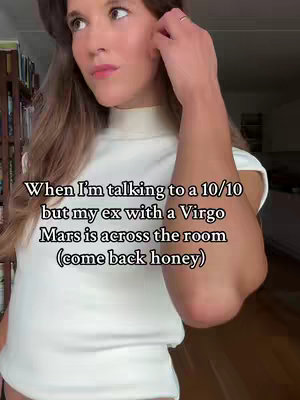 A woman with long brown hair and a white turtleneck pauses, her arm bent in front of her. Text overlays the image.