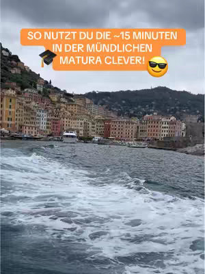 A scenic shot of a coastal town viewed from the water. Buildings line the shore, painted in various colors. The sky is overcast.  Text overlayed at the top.