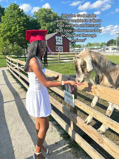 A young woman in a white dress and graduation cap stands beside a wooden fence, reaching out to pet a goat. Text overlays include a quote about love and action.