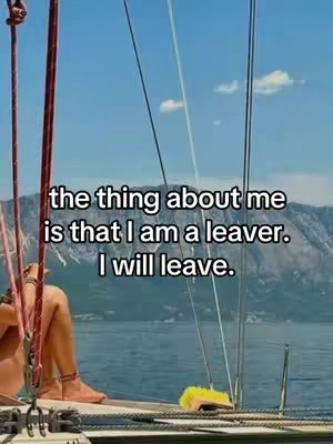 An image showing the partial view of a person on a boat with a bright blue sky and mountains in the background.