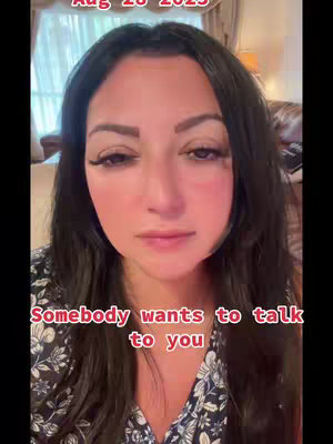 A woman with long black hair and a floral top is looking downwards at the camera with a somber expression. Overlayed in red font is the text "Somebody wants to talk to you". Above her is the date "Aug 28 2023". The composition is a close-up, focusing on her face and upper body.