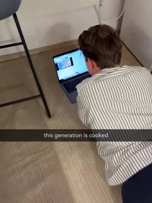 A person seen from the back is on the floor, looking at a laptop. The laptop screen displays a screen filled with content. Text overlayed at the bottom says, 'this generation is cooked'