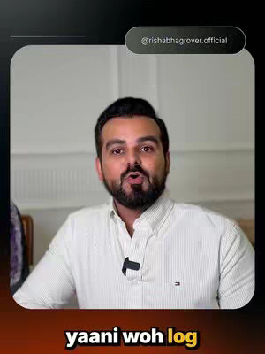 The image shows a man with a beard, dressed in a white collared shirt, speaking directly to the camera. Text overlays are added at the top-right and bottom-center of the enclosed image. The background is blurred, there is a black overlay framing the image, capturing a medium shot.