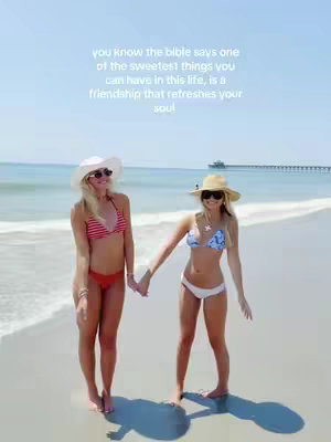 Two women in bikinis hold hands on a beach, smiling at the camera. Text overlay in a cursive font at the top states, 'you know the bible says one of the sweetest things you can have in this life, is a friendship that refreshes your soul'. The sky is clear blue and the sea is calm behind them.