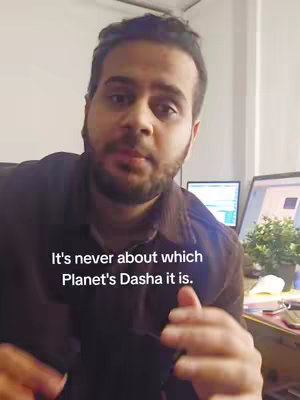 The image shows a man in a dark shirt speaking directly to the camera. He appears to be in an office setting with a screen and office decor in the background. Text is overlaid.