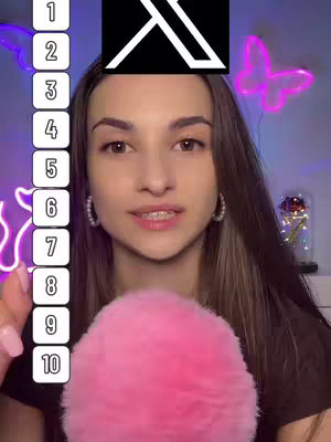 A young woman with long, dark brown hair is the central focus, her face taking up a substantial portion of the frame. She is looking directly at the viewer with a neutral expression, small hoop earrings visible. A large pink fluffy microphone is held in front of her. Her nails are painted with pink polish. Behind her are neon decor. On the left side, a vertical list of numbers from 1 to 10 is arranged. Above the image, in the center, a dark square is above the woman’s head that has a logo. The overall aesthetic is modern and clean, with a focus on the young woman.
