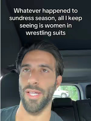 A selfie-style shot of a man in a car, the foreground dominated by his face and upper body. He is looking upwards with a slightly amused expression. Above him is the interior of the car's ceiling and an overlaid text, while in the background the outside world through the windows, including parts of another car and some trees. The overall tone is casual and conversational.