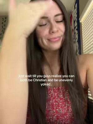 The cover image shows a woman with long brown hair, looking down with a subtle smile. She is wearing a red floral top. A part of her arm is visible and her hand is raised towards her face. Text overlayed on the image reads, 'Just wait till you guys realize you can both be Christian and be unevenly yoked.'