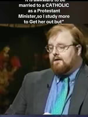 A man with glasses and a beard is seen in a medium shot. Text is added at the top of the frame. The background shows a vague, out-of-focus setting.