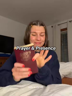 A woman in a dark blue sweater is in a bed, holding a maroon bible in her left hand and gesturing excitedly with her right hand. Overlaid on the image is the phrase "Prayer & Presence". The background shows a bedroom with a television and a window with blinds.