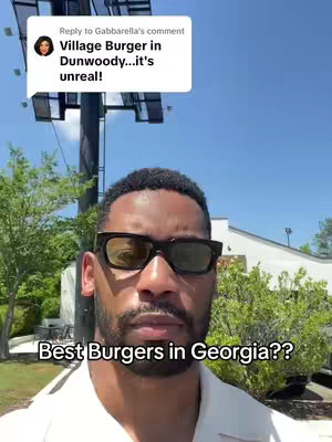 A man wearing sunglasses stands in front of a building with green foliage and the sky in the background. Text overlays appear on the image.