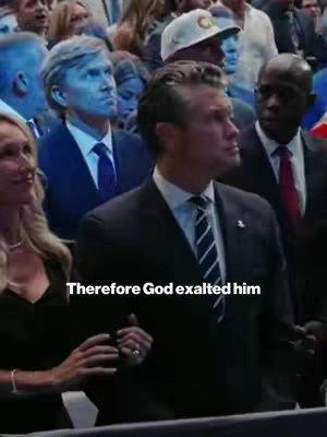 A candid cover photo showing a group of formally dressed people, with a man in a black suit, striped navy tie and a pin looking up and to his right. The background has other people, some looking up with the main person.