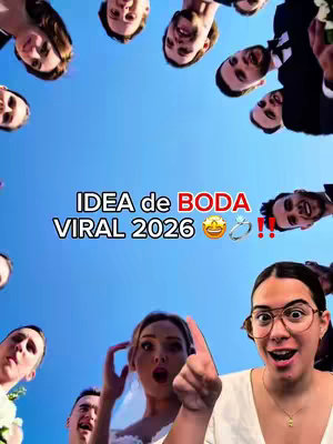 A selfie-style video cover features a woman in the lower right corner with a surprised expression, pointed finger and glasses, surrounded by a circle of individuals looking down towards the bottom of the frame. The backdrop is a bright blue sky, and bold white letters read "IDEA de BODA VIRAL 2026" above wedding ring emojis.