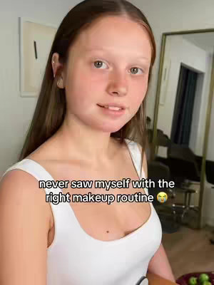 A young woman with long brown hair and fair skin is centered in the frame. She wears a white tank top and is looking towards the camera with a slight smile. Text is superimposed on the image.