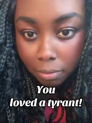 A close-up selfie of a dark-skinned woman with dark hair styled in braids. Her face is the primary focus, showing her eyes, nose, and lips in a neutral expression. The image includes added text overlayed on her face.