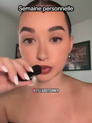 A close-up shot of a woman holding a microphone near her mouth, with overlayed text. She has smooth skin, dark eyebrows, and is wearing dark lipstick. There's text at the top and bottom. A picture is visible in the background.