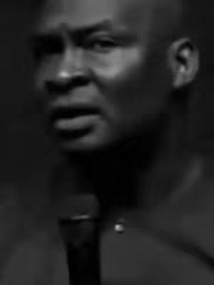 The cover image is a black and white close-up shot of a man, Apostle Joshua Selman. The man is bald and has a serious expression, looking slightly off-camera. The background is dark, which emphasizes the focus on his face and the top of a microphone he is holding. The lighting is positioned to create shadows that define his features, with the overall effect being a sense of solemnity.