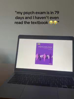 A laptop screen displays the cover of a psychology textbook. The screen is in the foreground, with the laptop keyboard partially visible below.