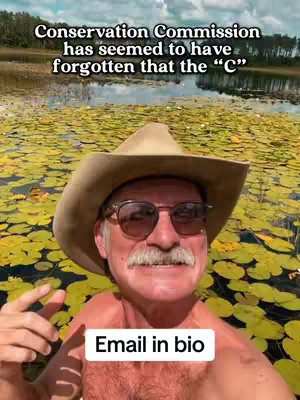 A man wearing sunglasses and a cowboy hat is in a body of water filled with lily pads, his chest is exposed with the image overlaid with text that states 'Conservation Commission has seemed to have forgotten that the "C"' and a smaller rectangular box that says 'Email in bio'