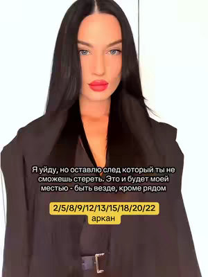 A woman with long black hair and bright red lipstick is centered in the frame, gazing directly at the viewer. She's wearing a dark outfit, possibly a blazer or coat, with a glimpse of a black camisole beneath. The background is plain, and the overall lighting is flattering. Text overlays are at the bottom, including a list of numbers. The composition is a selfie angle.