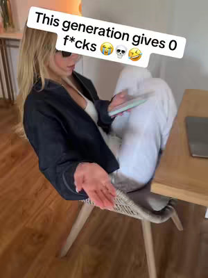 A young woman in sunglasses, wearing a black jacket and white pants, sits casually in a chair, holding a phone. A speech bubble with text and emojis overlays her head. The setting appears to be indoors with wooden flooring and a table nearby.