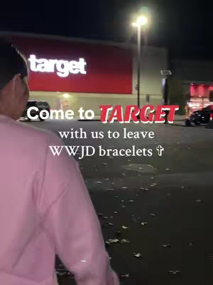 A night scene with a person walking towards a brightly lit Target store entrance. Text overlays are added to promote leaving WWJD bracelets at the store.