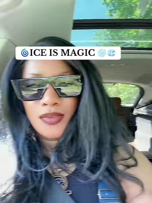 A woman is seen in what appears to be a car. She is wearing large sunglasses, dark hair and has dark lipstick. The text overlay reads "ICE IS MAGIC". The background windows give a glimpse of the outside world.