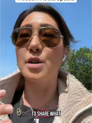 A woman with brown sunglasses and a light-colored jacket is in the frame, speaking to the camera. Text overlays are placed across the top and bottom of the frame.