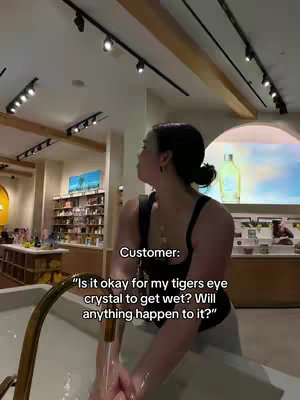The cover image showcases a woman standing near a sink, with water running from the faucet. She is looking away from the camera, and text is overlaid on the image. The environment looks like it is inside of a store, with lighting fixtures hanging from above and shelves of merchandise in the background.