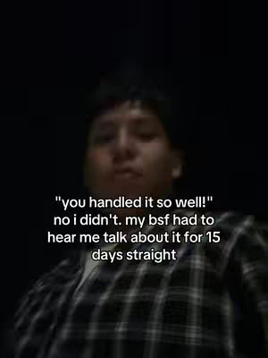 The image is a selfie-style shot featuring a young man from the chest up, centered against a dark backdrop. He is wearing a plaid shirt. Text overlays appear at the bottom half of the image, written in white font. The man's expression appears unclear due to low lighting.