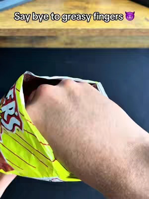 The cover image shows a close-up of a hand reaching into a yellow and red chip bag. The hand is fair-skinned and the bag is partially open, revealing the chips inside. Above the bag, on the background, is a wooden bar.