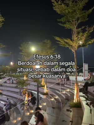 A night scene with tiered seating overlooking a public space with trees. A quote in Indonesian is overlaid on the image.