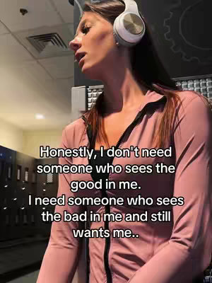 A woman wearing a pink jacket and white headphones is looking slightly to her left. Text is overlaid on the image.