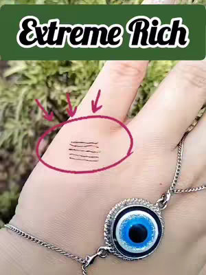 A hand is held up in front of leafy greenery, displaying a palm with lines circled in red and overlaid with a text box. The hand wears a blue eye charm bracelet.