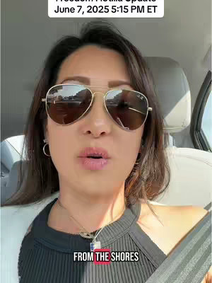 A woman wearing sunglasses is in the driver's seat of a car, looking towards the camera. Overlayed text indicates details about an event. The background is blurred but shows an outdoor scene.
