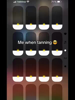 The image is a screenshot of an iPhone displaying what appears to be a settings menu. The background suggests a gradient of muted colors with a dark overlay of apps. The added text over the image reads "Me when tanning", with a sunglasses emoji. The layout features several rectangular UI elements with rounded corners, organized in a grid. The color scheme is dark with some white.
