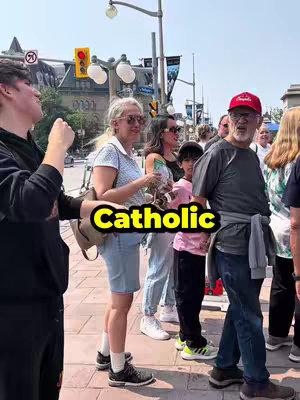 A photo of a street scene with several people, including a man with a red cap, a woman wearing sunglasses and holding a green item, and others looking towards the camera. The word 'Catholic' is overlaid prominently in a yellow box.